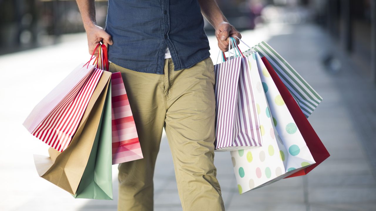 A man walks while holding several shopping bags.