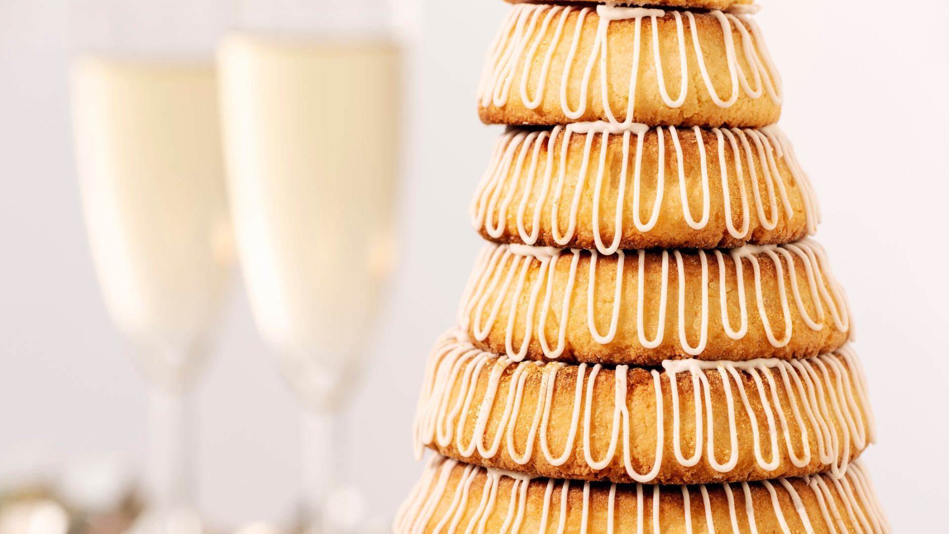 Several rings of Kransekage make up an impressive tower in front of some champagne glasses