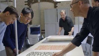 Erik Spikermann and two design students study a sheet of Bauhaus typography