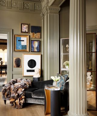 A light green room with columns and architectural details, plus a gallery wall of framed art