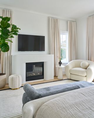 white bedroom with reeded fireplace and round white chair