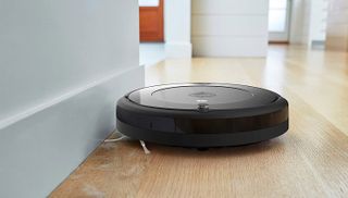 An iRobot Roomba 692 robot vacuum cleaner sweeping along an interior wall.