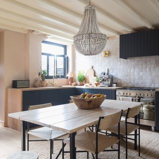 Dark grey L-shaped kitchen with pale worktops and pale zellige tiled splashback