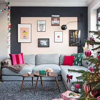 grey sofa with pink cushions under wall of prints