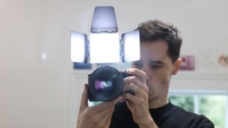 Zhiyun FIVERAY M20C LED panel mounted on a camera and held in front of a man's face
