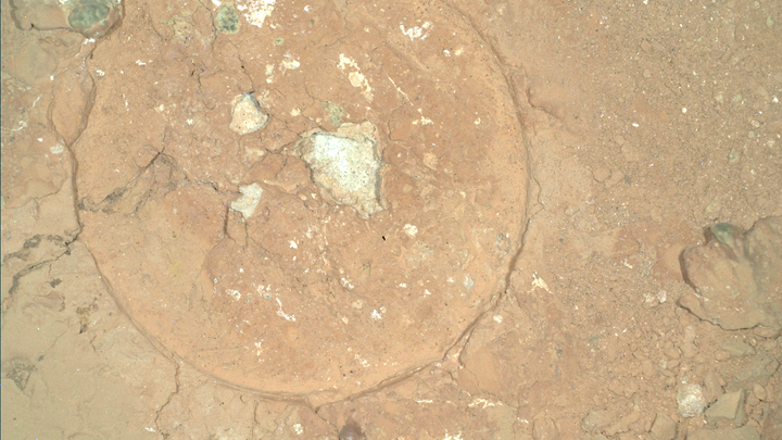 a brown rusty ground stamped with a circle toward the left side and green spots in Mars rock