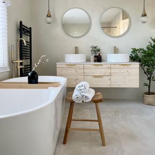 neutral bathroom with freestanding bath, wood vanity with double sinks and mirrors and gold taps