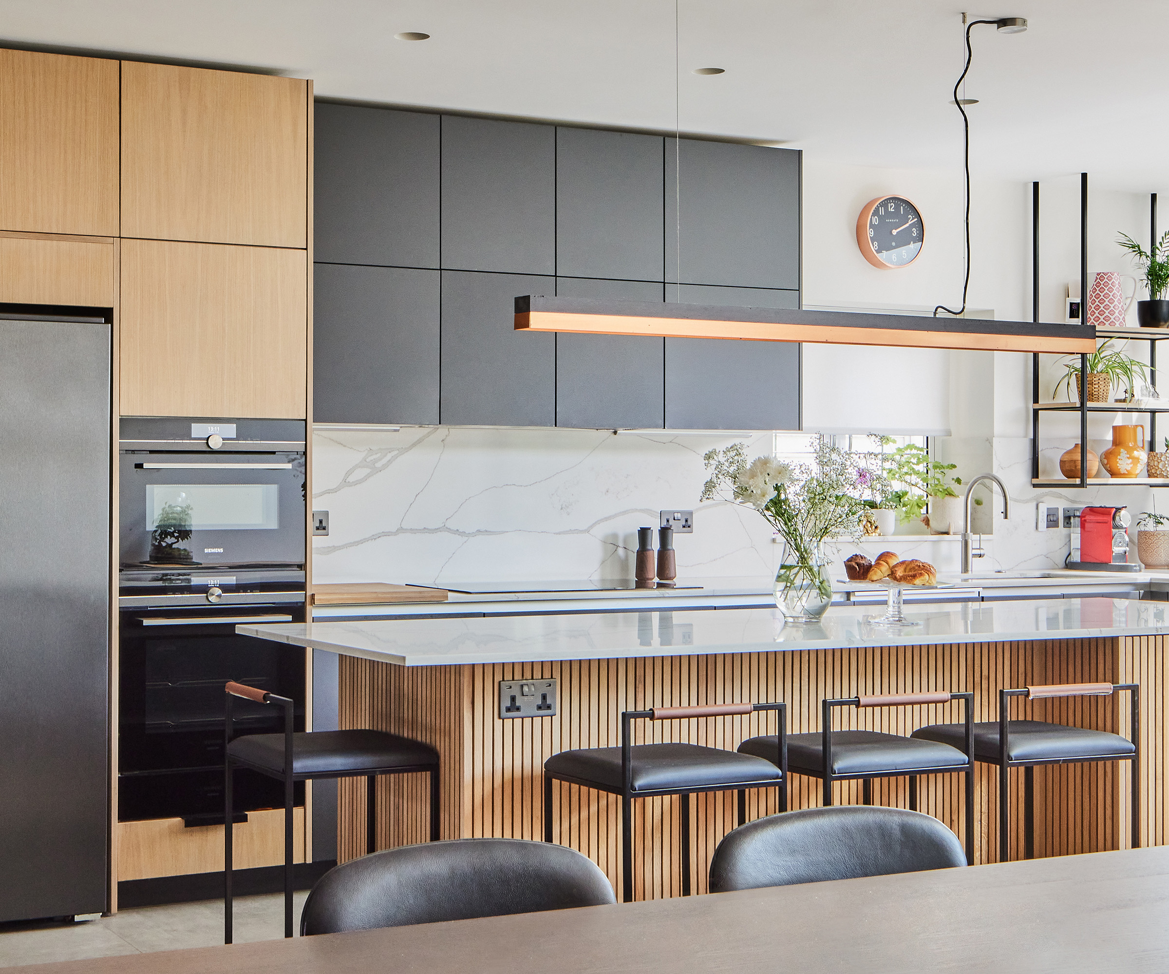 Wood and black cabinets in a kitchen with modern bar stools set up against a large kitchen island