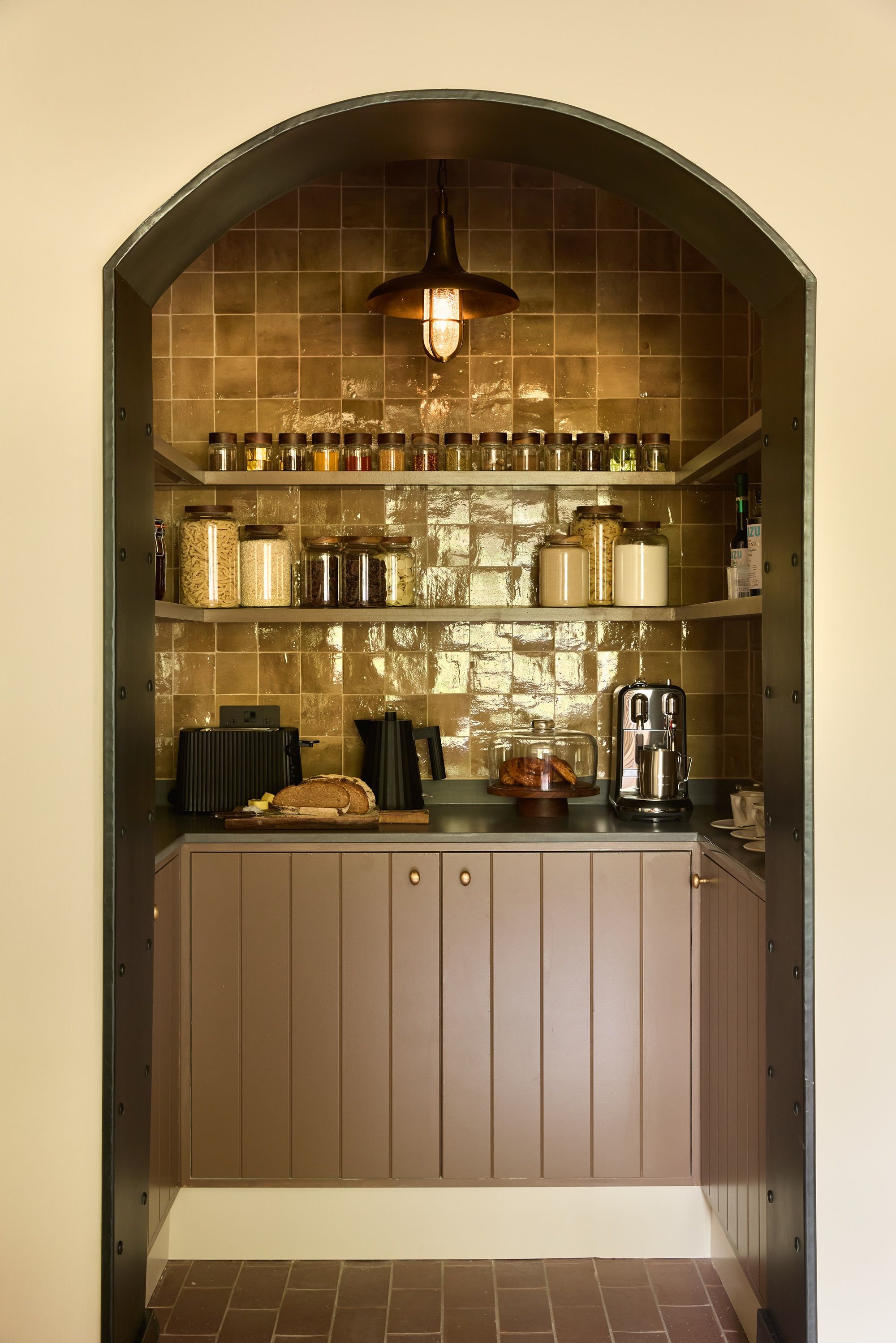 a pantry lined with zellig tiles in a warm yellow with brown cabinets