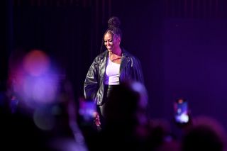 Michelle Obama smiles while taking the stage in a leather jacket and pants