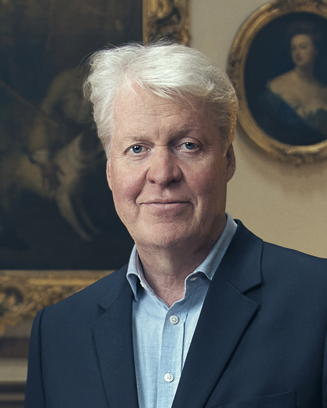 Charles Spencer wearing a navy blazer standing in front of paintings