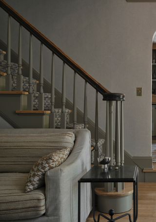 view of the living room and staircase. The room is all gray and the sofa is a two-tone, stripe and solid sofa