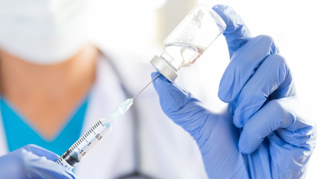 gloved woman drawing vaccine from vial