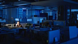 A worker sits in an empty office at night (illustrative, but not literally, a game development studio)
