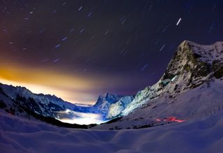 A long exposure photo shows the stars above Eiger mountain overlooking the Swiss village of Grindelwald