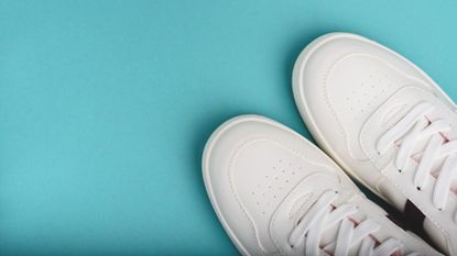 A pair of clean white sneakers pictured against a blue background