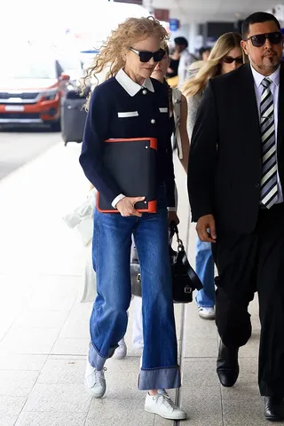 Nicole kidman wears a navy jacket, blue cuffed jeans, and white sneakers.