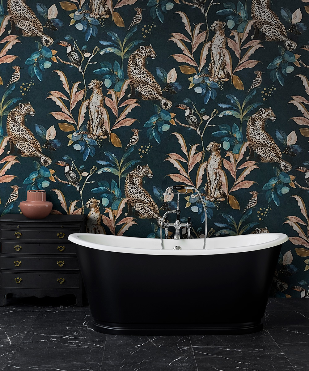 Dark leopard and leaf print wallpaper and black bathtub show the black bathroom trend.