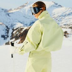 a model wears a yellow jacquemus + nike ski jacket on the slopes