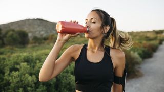 Woman drinking an isotonic drink after a run