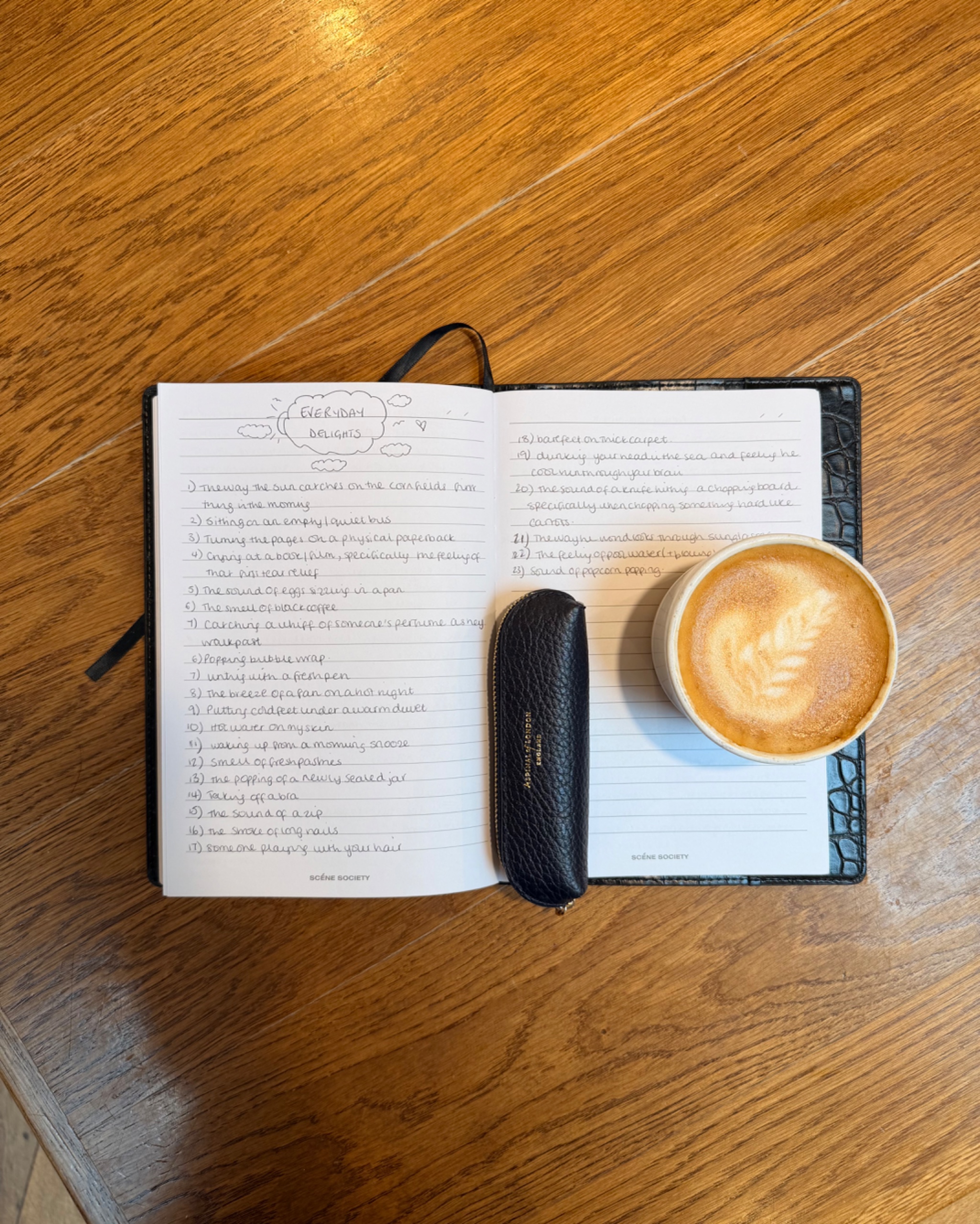 An open journal with hand writing across both pages next to a coffee cup