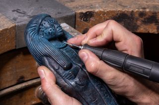 craftsperson works on sculpture of mythical figure