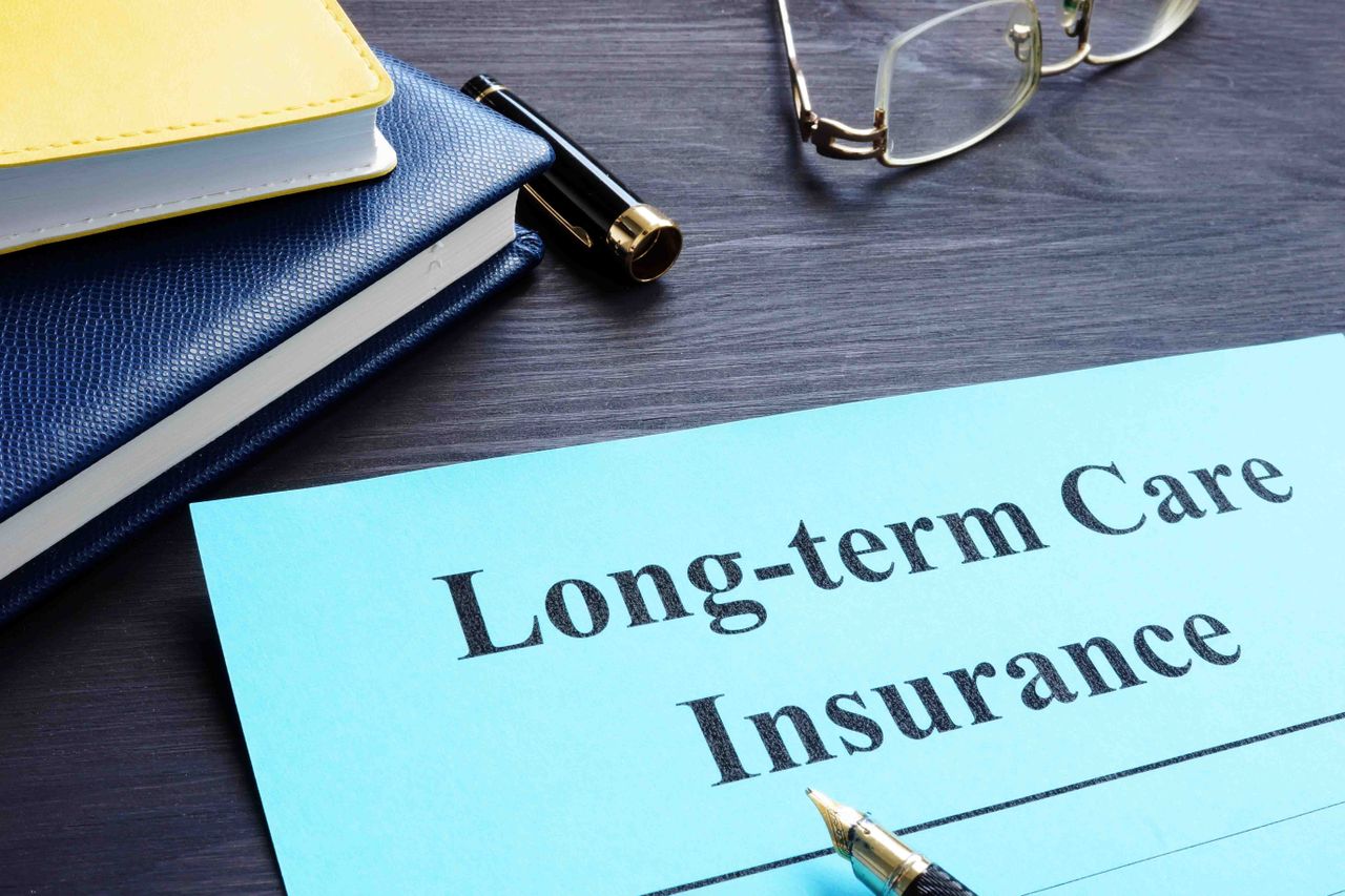 Items on a desk including glasses and a paper reading &quot;long-term care insurance.&quot;