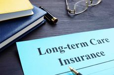 Items on a desk including glasses and a paper reading "long-term care insurance."