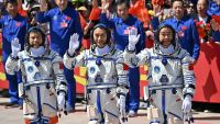 A photo of three Chinese astronauts waving to the cameras before launching to space