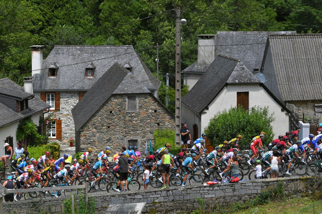 The peloton climb through a town on stage 14