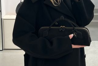 Eliza Huber holding the new black suede Alaïa Le Teckel clutch in the brand's Paris flagship store.