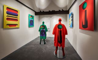 A white gallery space with two mannequins in bright outfits