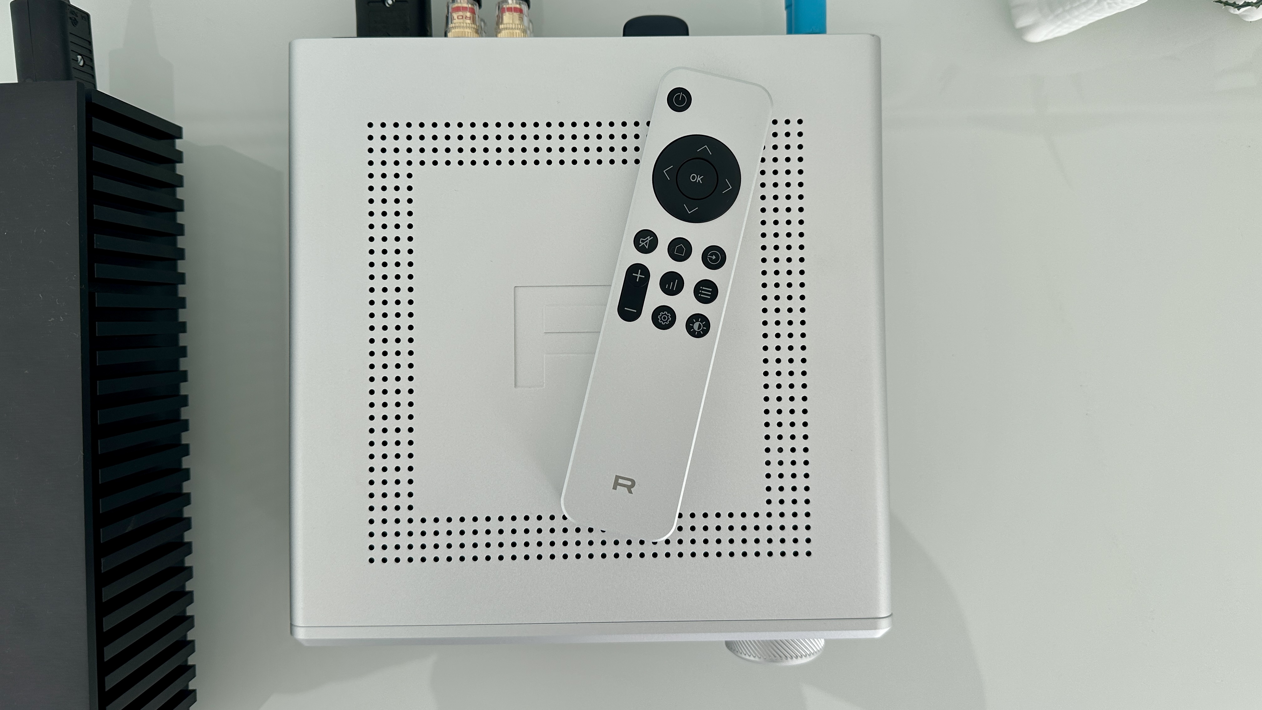 Rotel's DX-5 integrated amp in silver on a light gray table, with the amp's remote visible