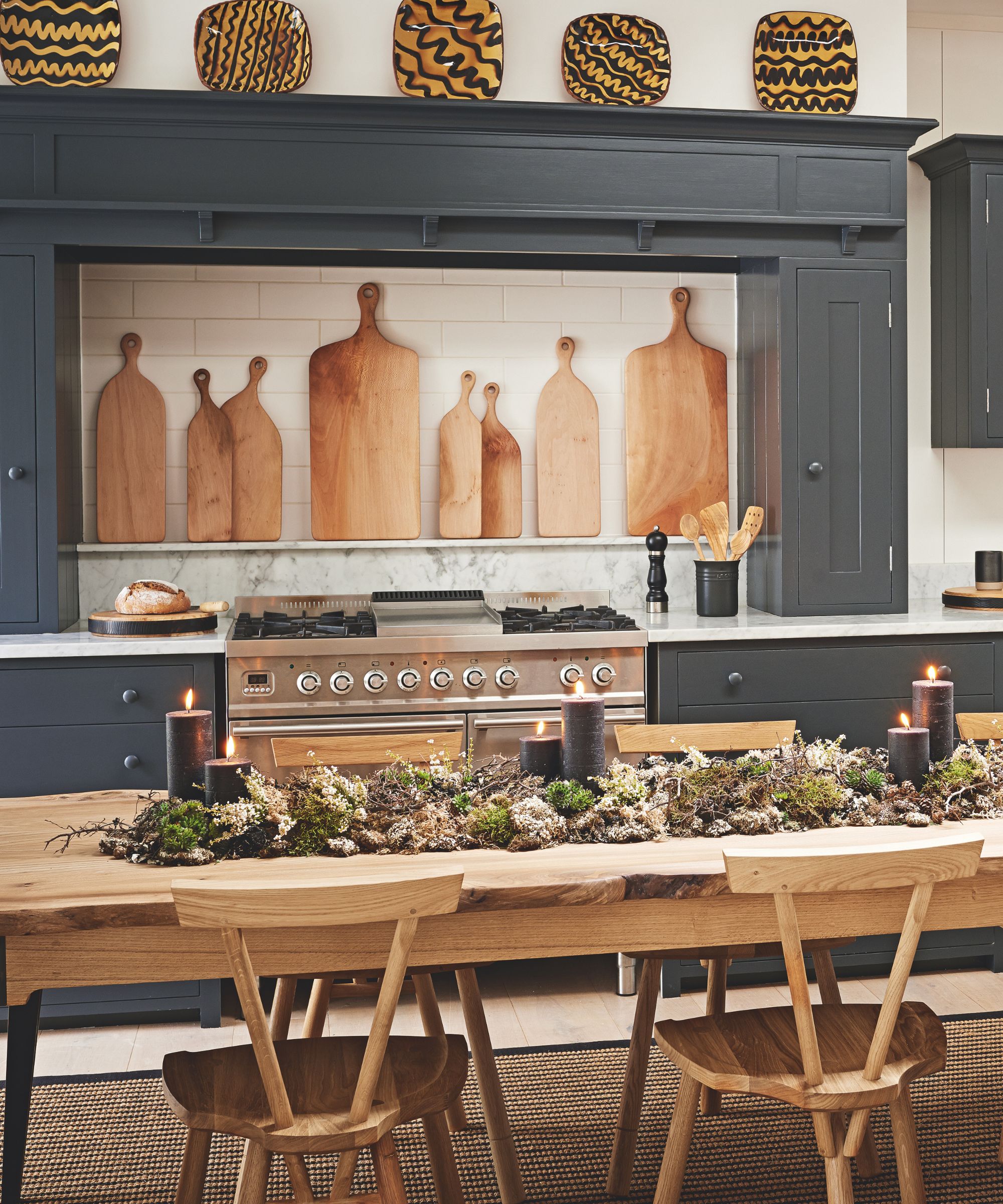 Kitchen with wooden boards and a christmas garland and black pillar candles on a dining table