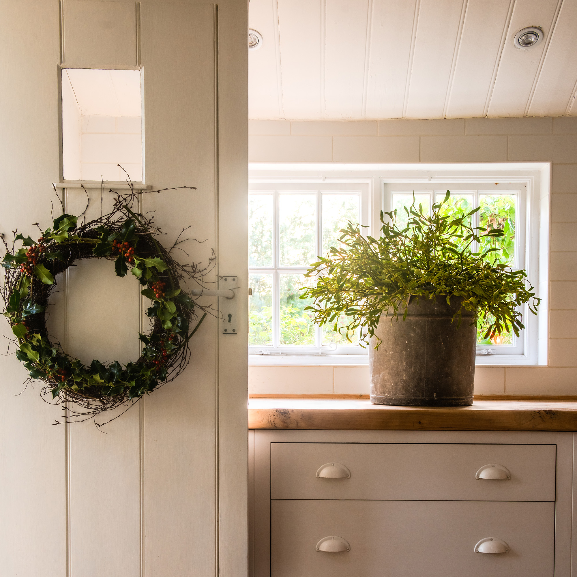 neutral kitchen with cream cabinets and wooden worktops dressed for christmas with mistletoe and festive foliage 1
