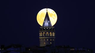 A large full moon behind a tower in Instanbul