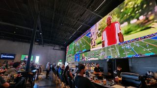 A <AXHUB 50-foot-wide display shows sports to bar patrons. 
