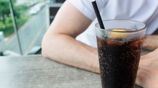 man sitting next to a glass of diet soda