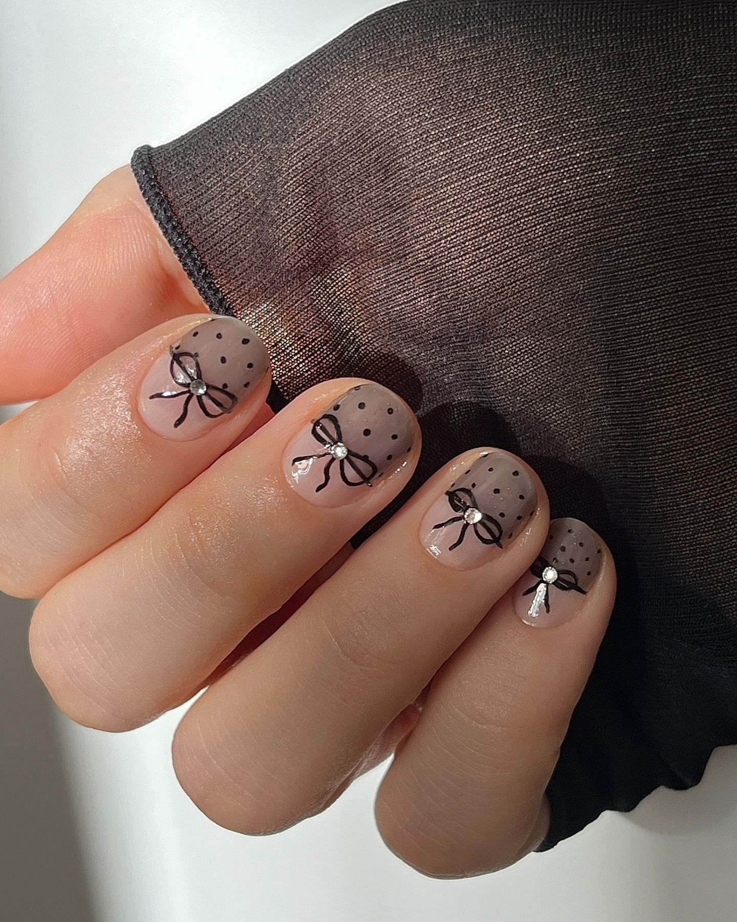 A mole brown manicure with black bows and polka dots