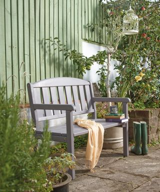 Garden bench on patio in front of garden fence painted grey