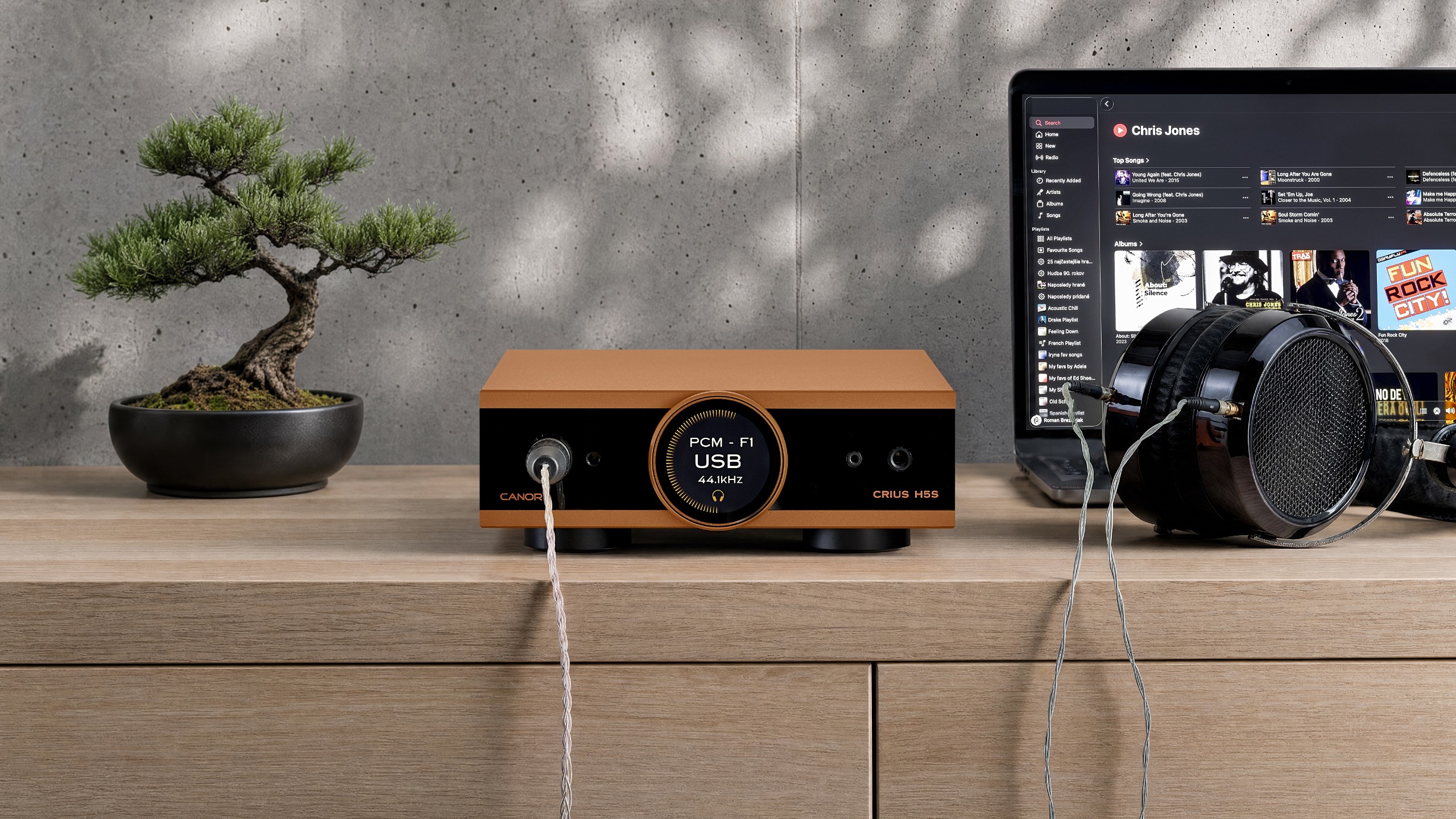 Canor Crius H5S DAC/headphone amplifier on a wooden surface next to a pair of headphones 