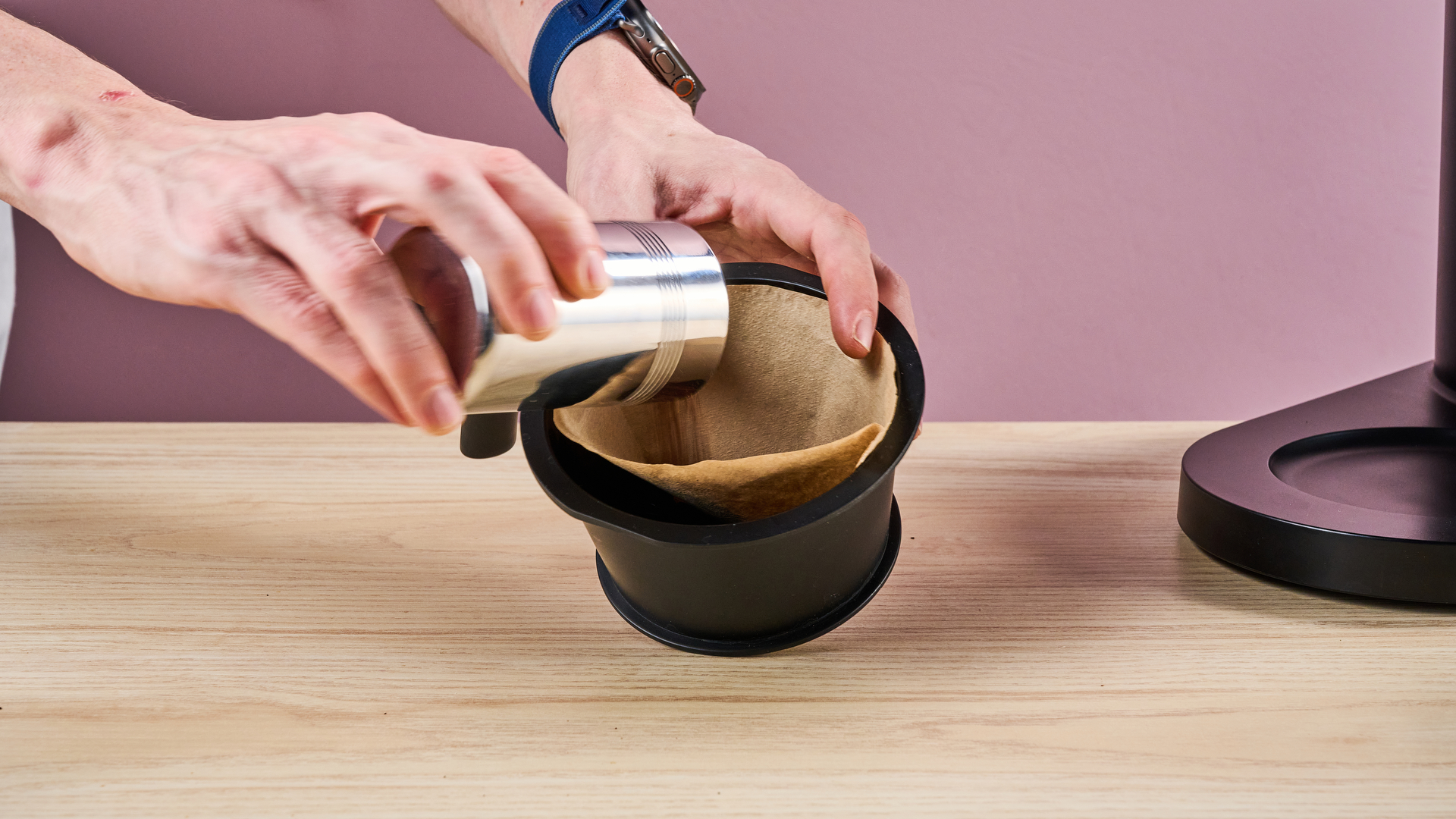 A man pours coffee grounds into the filter paper inside the Ratio Four's filter basket.