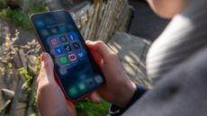 A 14-year-old boy holds a phone with various social media apps. 