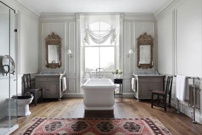 grand bathroom with roll top bath and vintage mirrors, white window blind