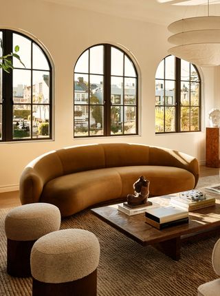 a neutral living room with a curved amber color sofa