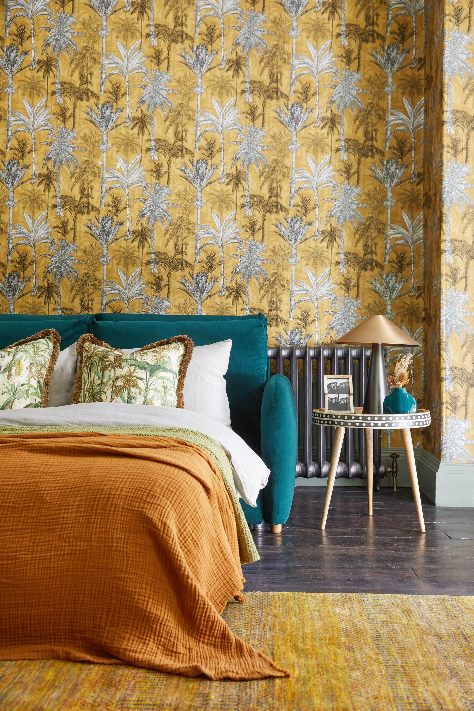 Sleeper sofa extended into bed in room with wood floor and patterned wallpaper