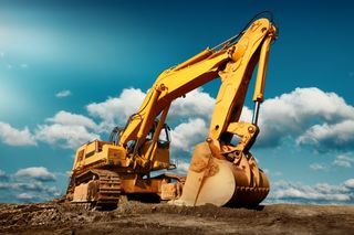 Large excavator on construction site on a sunny day with blue sky and fluffy clouds