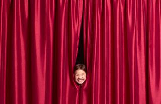 9 year old girl putting face through curtains