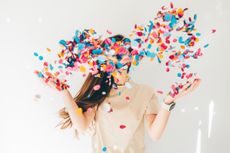Woman celebrating with confetti on white background.