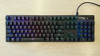 full-size black HyperX wired keyboard against light wood background